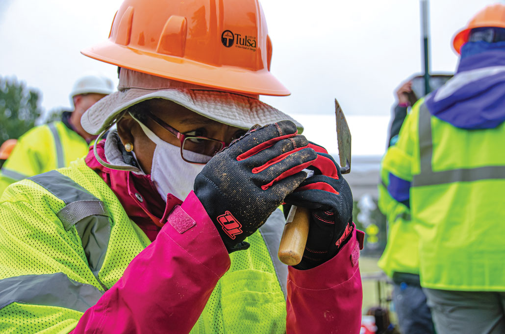 Phoebe Stubblefield looks closely at something in her hands while holding a trowel