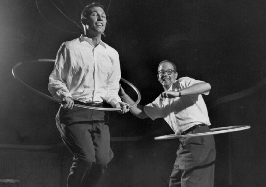 black and white image of two men using hula-hoops