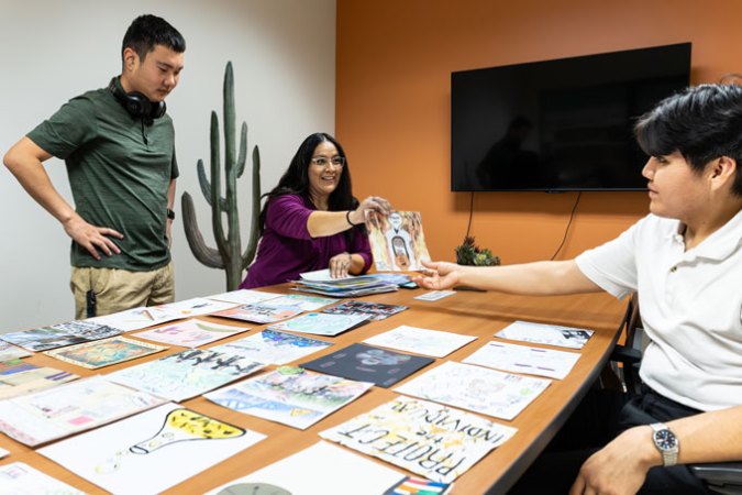 Krystal Tsosie and students Jonathan Kim and Kai-Se Toledo review art created by students in the Biology and Society course at Arizona State University.