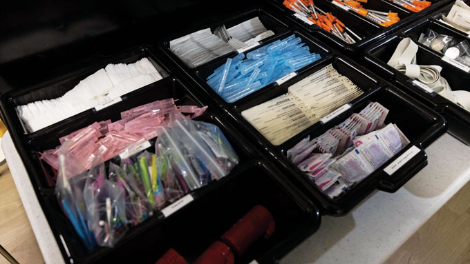 Needles, gause, bandages, syringes shown in a black container.