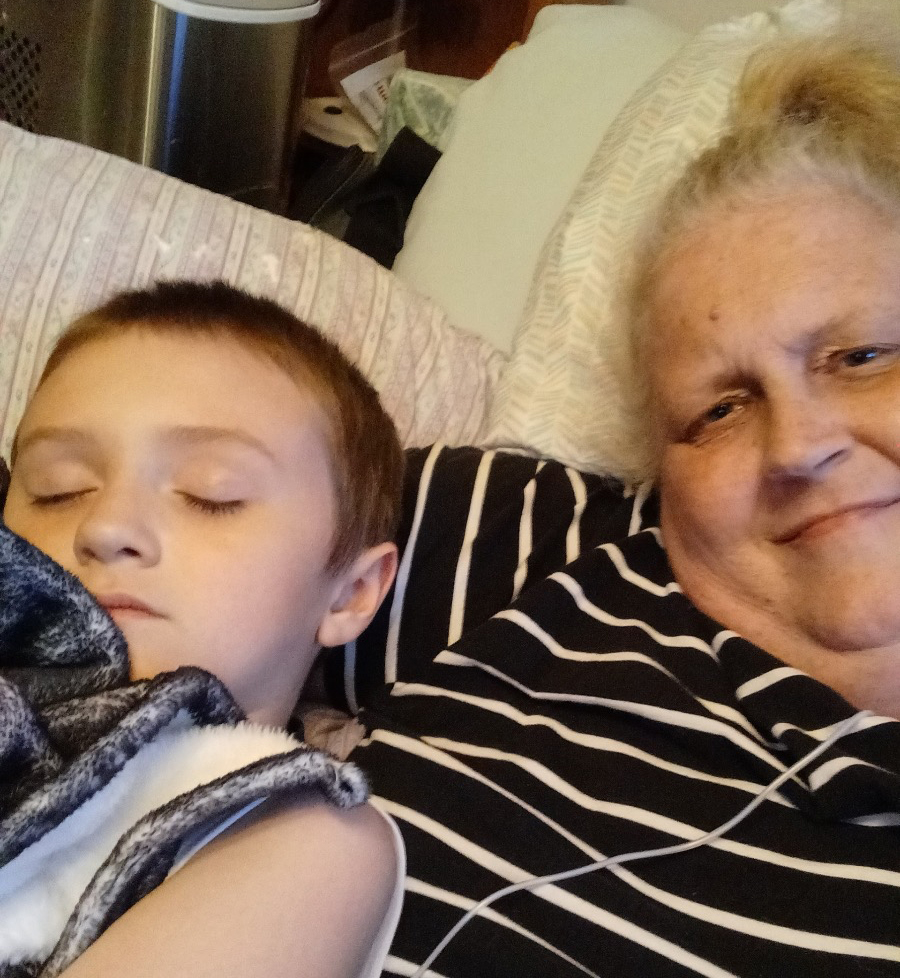 A photo of an older woman taking a picture with her young grandson.