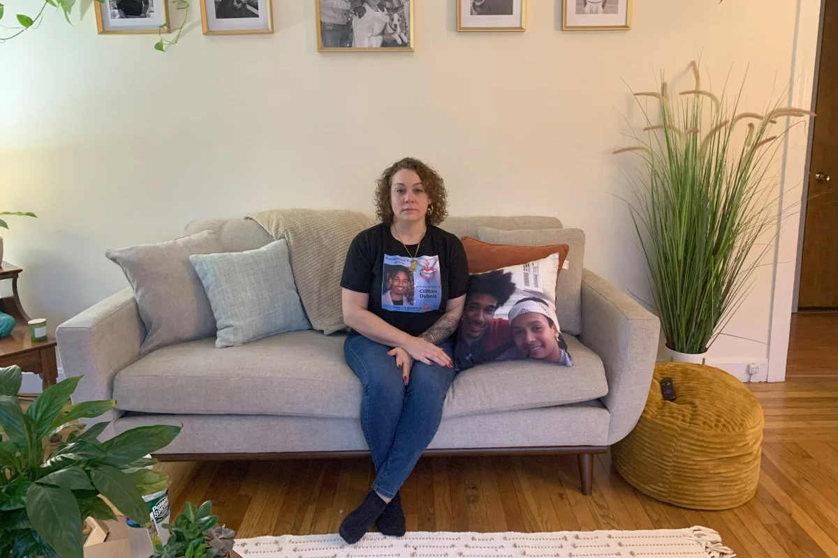 A woman sits on a couch and looks at the camera.